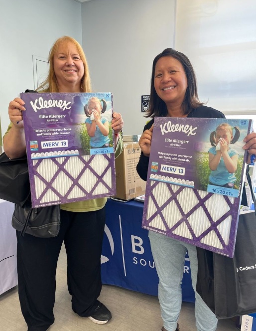 Community members holding Kleenex® Elite Allergen MERV 13 Certified Kleenex® air filters at a donation event.