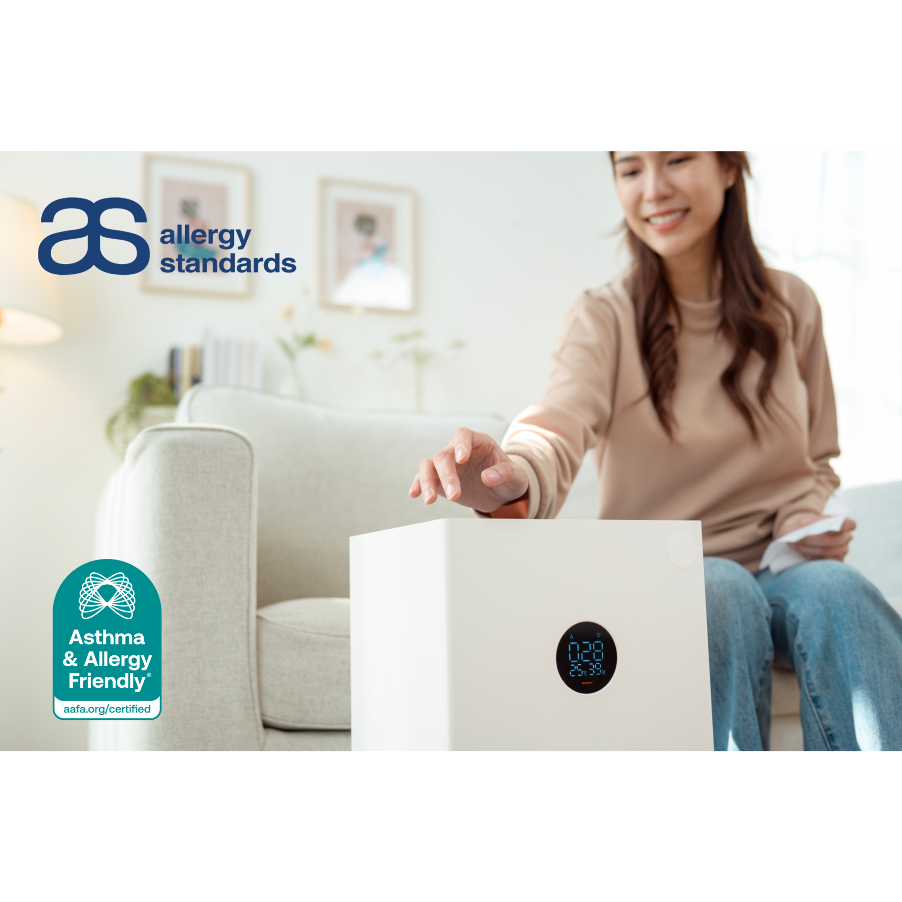 A woman adjusting a compact portable air purifier in her living room, representing the Asthma & Allergy Friendly® Certification Program’s updated standard for smaller certified air cleaners.